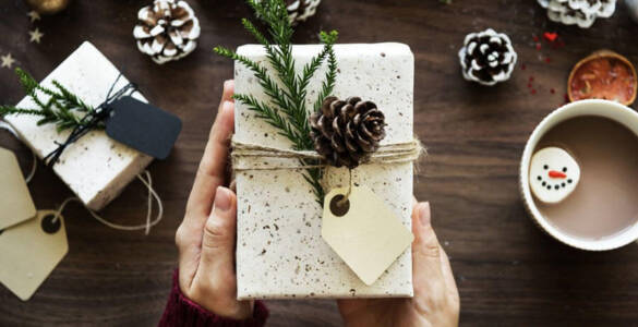 białe pudełko prezentowe z kokardką w rękach na świątecznym stole