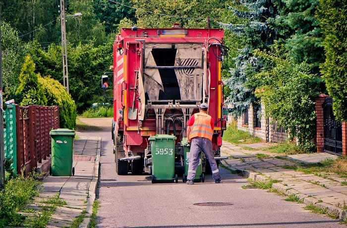 śmieciarka podczas odbierania śmieci na osiedlu domków jednorodzinnych