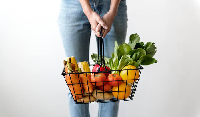 kobieta trzymająca koszyk z warzywami w dłoniach